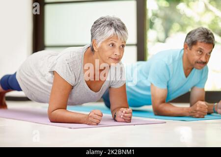 Wir konzentrieren uns gegenseitig auf Fitness. Aufnahme eines reifen Paares, das zu Hause gemeinsam trainiert. Stockfoto