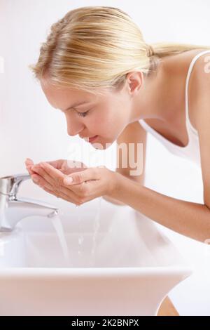 Erhaltung einer gesunden und schönen Haut. Aufnahme einer attraktiven jungen Frau, die ihr Gesicht über einem Waschbecken mit Wasser wäscht. Stockfoto