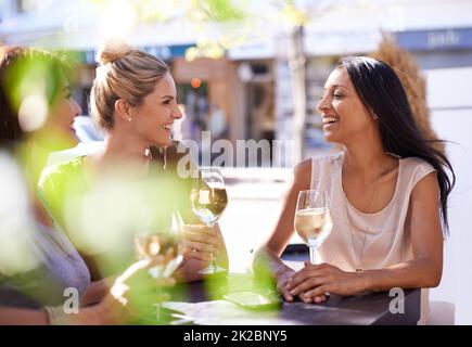 Es ist ein bisschen ein Weinkenner. Eine kurze Aufnahme von drei Frauen, die in einem Straßencafé ein Glas Weißwein genießen. Stockfoto