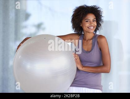 Mein Fitnessgeheimnis. Beschnittenes Porträt einer attraktiven jungen Frau, die mit einem Übungsball steht. Stockfoto