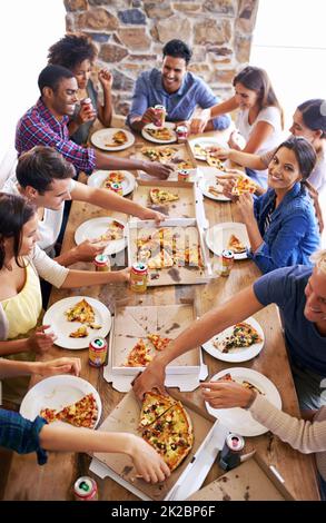 Sich für Pizza treffen. Eine kurze Aufnahme einer Gruppe von Freunden, die zusammen Pizza genießen. Stockfoto