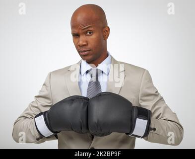 Bereit, alle geschäftlichen Mitbewerber zu übernehmen. Studioaufnahme eines afroamerikanischen Geschäftsmannes mit Boxhandschuhen. Stockfoto