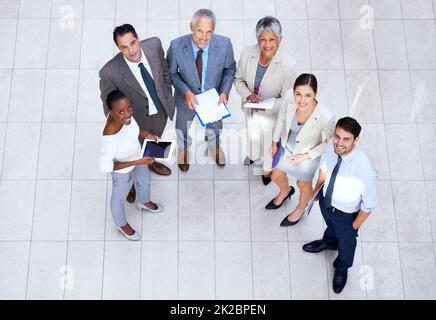 Sie wissen, was sie tun. Porträt einer Gruppe von Geschäftsleuten, die Papierkram und ihre digitalen Geräte halten. Stockfoto