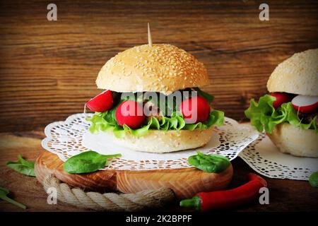 Hausgemachte Burger mit Rindfleisch, Radieschen, Salat, auf hölzernen Hintergrund serviert. Stockfoto