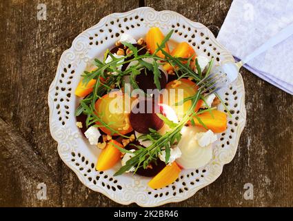Gesunde Rüben Salat mit roten, weißen und goldenen Rüben, Rucola, Muttern, Feta Käse auf Holz- Hintergrund Stockfoto