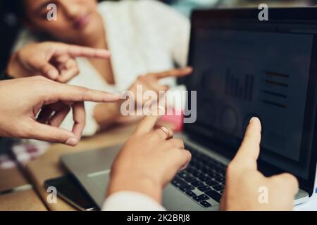 Sehen Sie sich die Zusammenarbeit an. Eine kurze Aufnahme von nicht erkennbaren Designern, die auf Informationen auf einem Laptop-Bildschirm in einem Café zeigen. Stockfoto