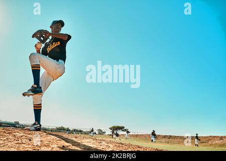 Mach dich fertig. Aufnahme eines jungen Baseballspielers, der den Ball während eines Spiels im Freien anspielt. Stockfoto