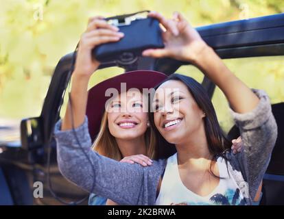 Wertvolle Momente zwischen Freunden festhalten. Aufnahme einer zwei Freundinnen, die auf einer Roadtrip-Reise Selbstporträts machen. Stockfoto