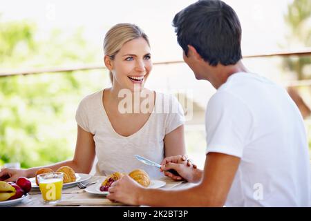 Wir haben ihren Aufenthalt im Bed & Breakfast genossen. Aufnahme eines glücklichen jungen Paares, das zusammen auf der Terrasse zu Hause frühstückte. Stockfoto