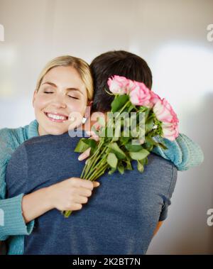 Du hast gerade meinen Tag gemacht. Aufnahme eines liebevollen jungen Mannes, der seiner schönen jungen Frau einen Strauß rosa Rosen gab. Stockfoto