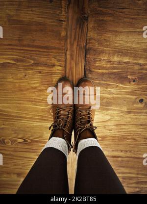 Rustikaler Stil. POV-Aufnahme einer Person, die Stiefel trägt und auf einem Holzboden steht. Stockfoto