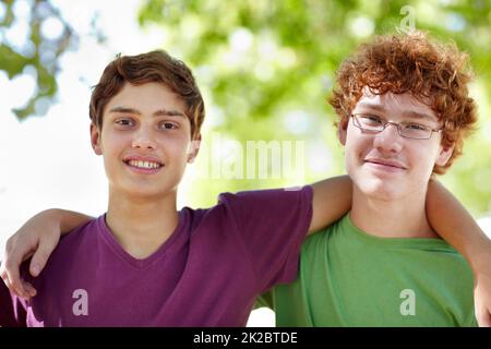 Zwei Erbsen im Park. Porträt von zwei Jungen im Teenageralter, die im Park hängen. Stockfoto