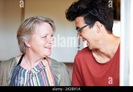 Sie haben einen ähnlichen Sinn für Humor - Mutter und Sohn. Junger Mann, der zu Hause mit seiner Mutter einen Witz teilt. Stockfoto