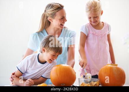 Kürbisse schnitzen mit Mama. Eine Mutter, ihr Sohn und ihre Tochter höhlen zu halloween Kürbisse aus. Stockfoto