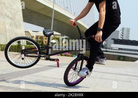 Zeigt sein Können. Eine abgeschnittene Ansicht eines Radfahrers, der einen Trick auf seinem Fahrrad macht. Stockfoto