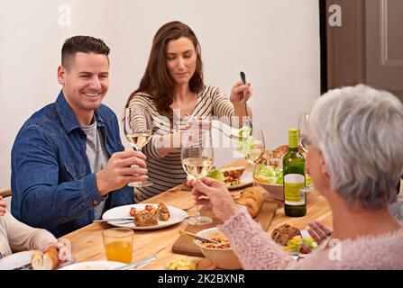 Prost. Eine kurze Aufnahme einer Familie, die am Esstisch ein Essen teilt. Stockfoto