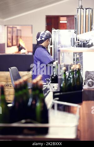 Arbeiten in der Abfüllanlage. Aufnahme eines Arbeiters in einer Weinabfüllanlage. Stockfoto