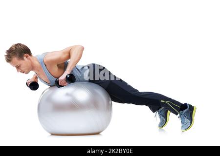 Wirklich die Arme zu arbeiten. Aufnahme eines Mannes, der auf einem Gymnastikball Gewichte hebt. Stockfoto