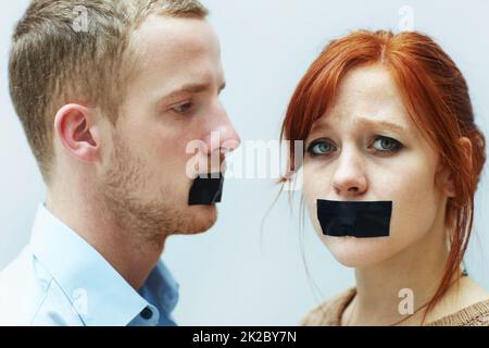 Sie wurden zum Schweigen gebracht. Ein junges Paar, das traurig mit Klebeband über dem Mund aussieht. Stockfoto