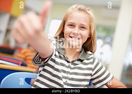 Meine Schule ist fantastisch. Sweet Grundschule Mädchen geben Ihnen einen Daumen nach oben - konzentrieren Sie sich auf den Hintergrund. Stockfoto