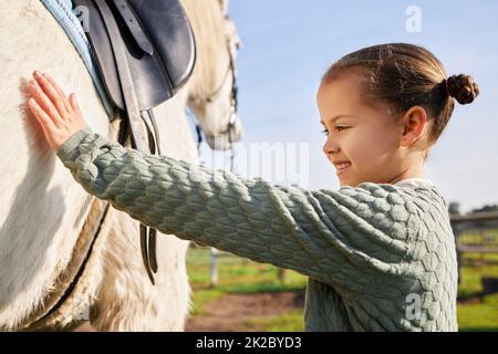 Eine junge Reiterin und ihr Pferd. Kurzer Schuss eines entzückenden jungen Mädchens, das ihr Pferd draußen auf der Ranch streichelte. Stockfoto