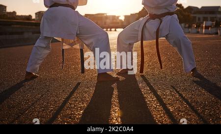 Bereit für den Kampf. Zwei Sportler stehen sich gegenüber und üben ihr Karate, während sie GI tragen. Stockfoto