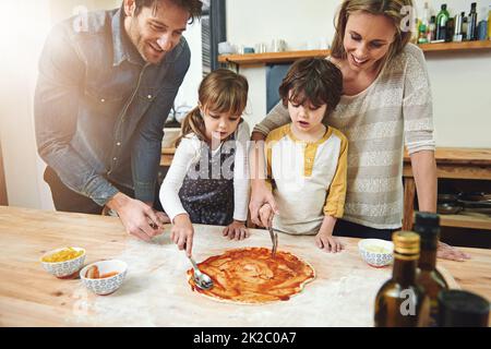 Die Küchen sind ideal für Familien. Eine Familie, die Pizza zu Hause genießt. Stockfoto