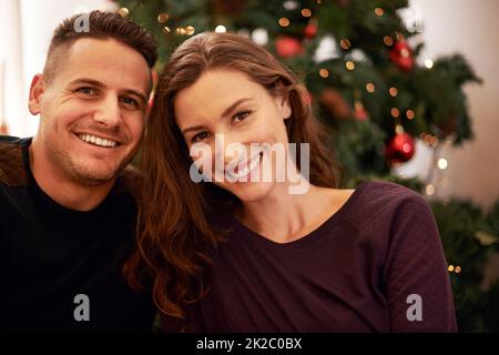 Unser erstes gemeinsames Weihnachtsfest. Porträt eines glücklichen jungen Paares am Weihnachtstag. Stockfoto