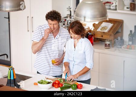 Etwas gesundes kochen. Ein glückliches reifes Paar, das zu Hause gemeinsam eine gesunde Mahlzeit zubereitet. Stockfoto