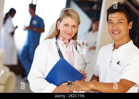 Fürsorgliche Gesundheitsfachkräfte. Aufnahme von zwei Medizinern, die die Kamera anlächeln. Stockfoto