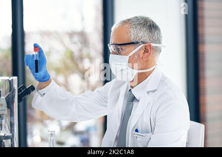 Leben retten ein Experiment nach dem anderen. Ausgeschnittene Aufnahme eines Wissenschaftlers, der in einem Labor ein Reagenzglas untersucht. Stockfoto