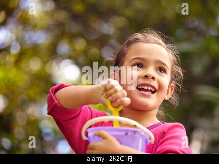 Sommerspaß. Aufnahme eines kleinen Mädchens, das draußen im Schlamm spielt. Stockfoto