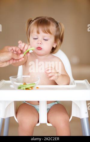 Gesunde Snacks. Ein süßes kleines Mädchen, das von ihrer Mutter gefüttert wird. Stockfoto