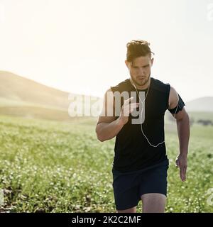 Auf lange Sicht in der IT. Kurzer Schuss eines hübschen jungen Mannes, der im Freien läuft. Stockfoto