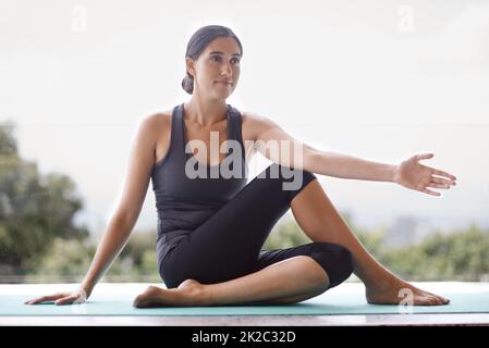 Beginnen Sie Ihren Tag mit einer guten Yoga-Sitzung. Ganzkörperaufnahme einer jungen Frau, die Yoga macht. Stockfoto