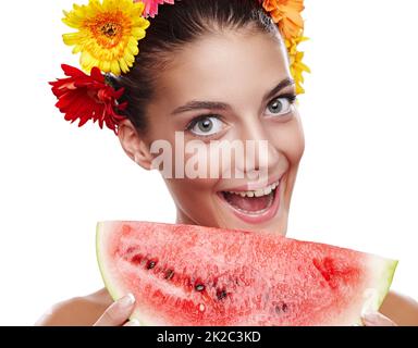 Verrückt nach Wassermelone. Beschnittenes Porträt einer schönen jungen Frau, die eine Blumenkrone trägt und eine Wassermelone isst. Stockfoto