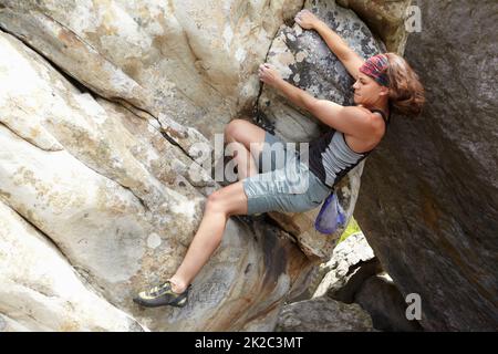 Ein anspruchsvolles Manöver. Ein Felskletterer, der an einer Felswand hängt. Stockfoto