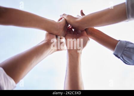 Waren ein Team, das motiviert bleibt. Aus dem niedrigen Winkel eine unerkennbare Gruppe von Geschäftsleuten, die zusammenstehen und sich gegenseitig eine hohe fünf geben. Stockfoto