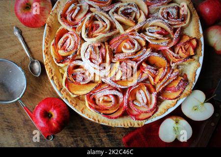 Traditioneller Kuchen mit apfelförmigen Rosen, Obstdessert, Torte auf einem rustikalen Holztisch. Draufsicht Stockfoto