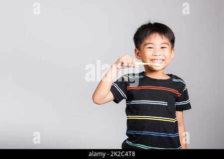 Kleiner süßer Junge, 5-6 Jahre alt, der Zähne putzt und im Studio lächelt, isoliert Stockfoto