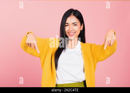 Ein lächelnder Frauenständer macht eine Geste mit zwei Fingern, die nach unten zeigen Stockfoto