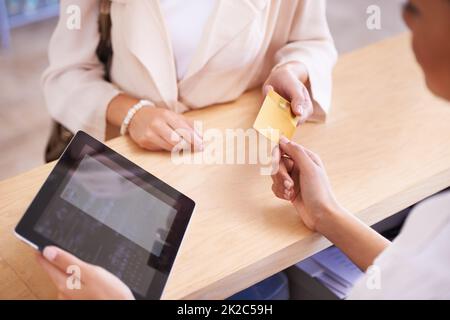 Lade es auf meine Karte. Eine junge Frau, die ihre Kreditkarte einem Verkäufer übergibt. Stockfoto