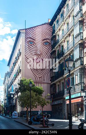 Großes Wandgemälde mit dem Gesicht einer Frau hoch auf der externen Parteiwand des Gebäudes, Calle de la Magdalena, Madrid, Spanien. Stockfoto