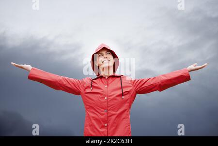 Ich bin auf alles vorbereitet. Kurzer Schuss einer attraktiven jungen Frau, die im Regen steht. Stockfoto