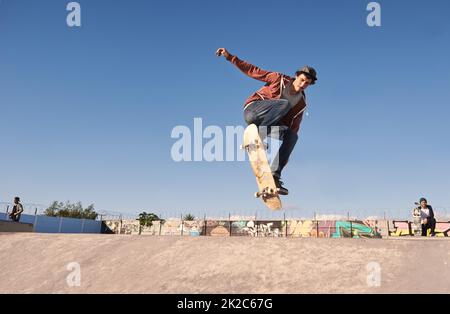 Luft holen. Ein junger Mann macht Tricks auf seinem Skateboard im Skatepark. Stockfoto