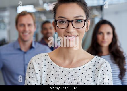 Shes hat die Vision. Zugeschnittenes Porträt einer jungen Frau mit ihren Mitarbeitern im Hintergrund. Stockfoto