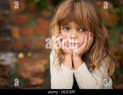 Scheut das niedliche Messgerät ab. Kurzer Schuss eines niedlichen kleinen Mädchens, das an einem Herbsttag draußen sitzt. Stockfoto