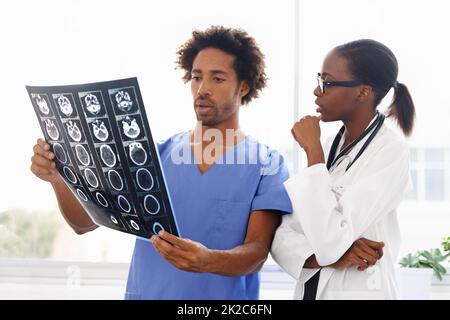 Lernen, wie Scans gelesen werden. Aufnahme einer Ärztin und eines Krankenpflegers, die einen CAT-Scan untersuchen. Stockfoto