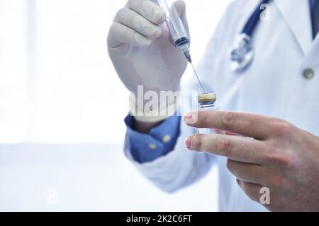 Sind Sie geimpft? Zugeschnittenes Bild eines männlichen Arztes, der eine Spritze mit Medikamenten füllte. Stockfoto