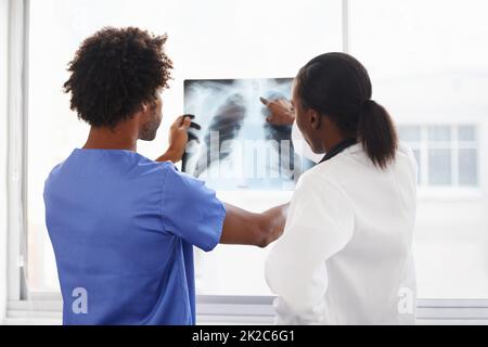 Röntgeneinblicke in den Körper. Aufnahme einer Ärztin und eines Krankenpflegers, die Röntgenaufnahmen studieren. Stockfoto